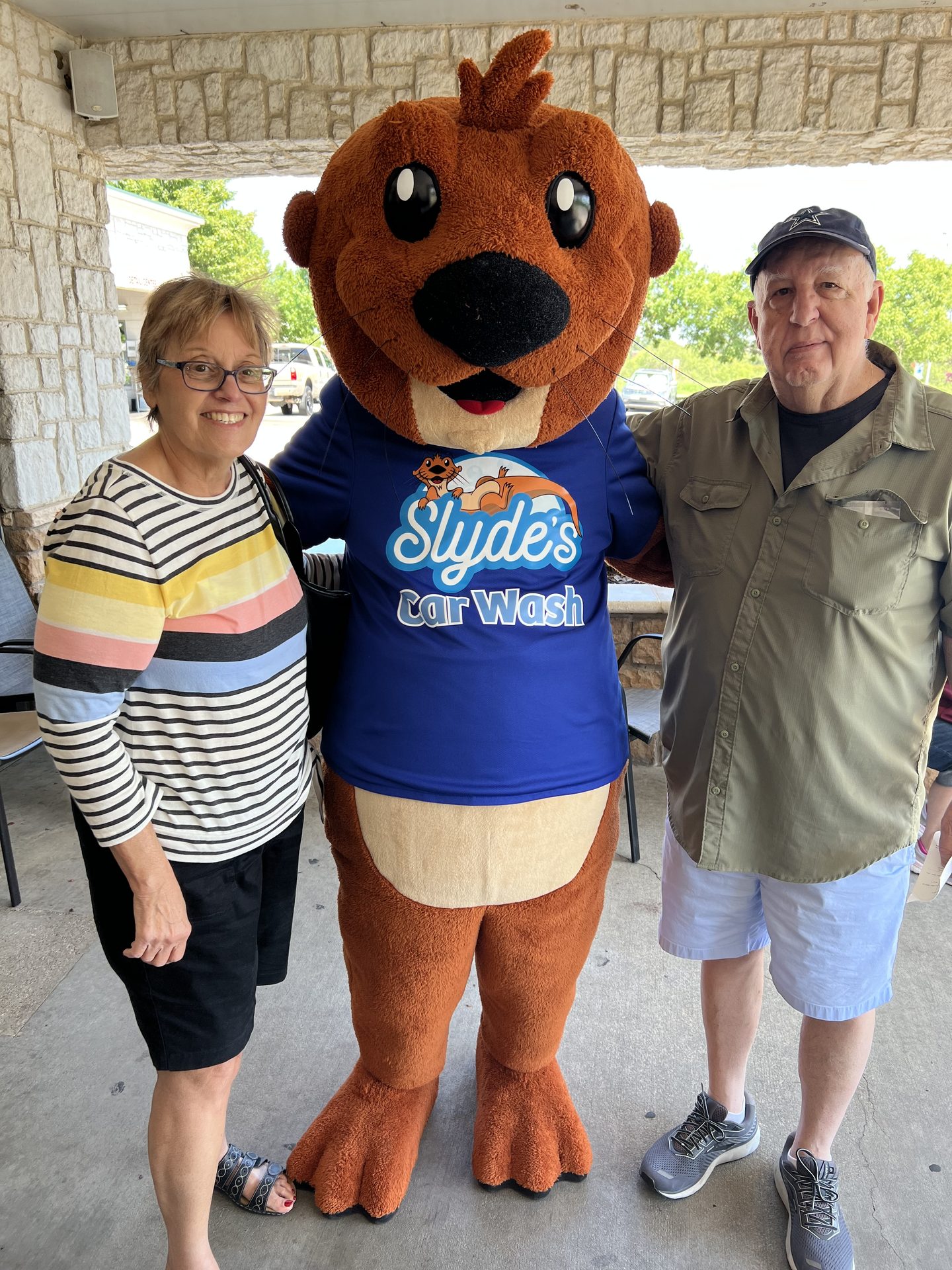 Slyde the otter mascot posing with two happy guests